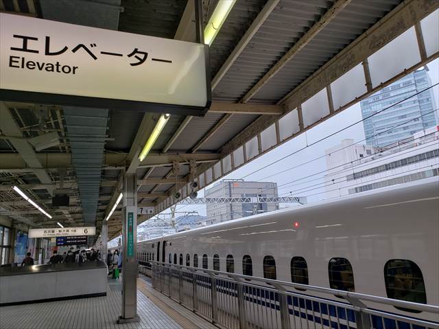 20220429_121936_R 小田原駅でほーむから発車するこっちを立派なカメラで撮影する８歳ぐらいの女の子ユーチューバー。新幹線のスピードに合わせてカメラを振る。隣にお父さん