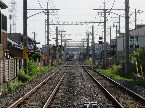 踏切から大宮方面を見る。東武60000系電車は八木崎駅に停車中。